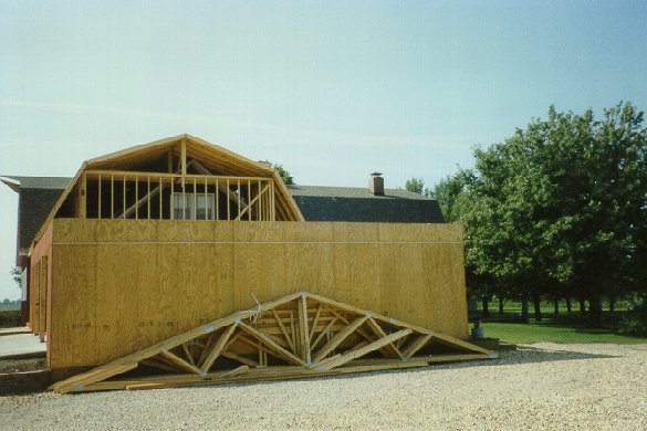 Roof trusses are stock-piled against the north wall of the garage